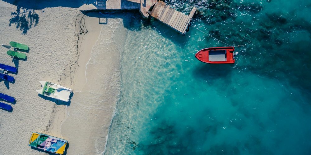 red boat on body of water near brown wooden foot board